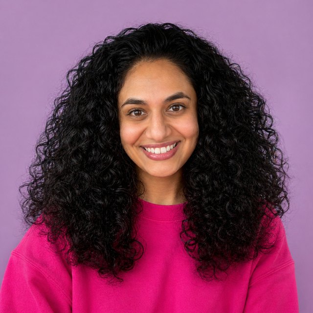 Dina Hamed smiling, wearing a bright pink sweatshirt on a lavender background